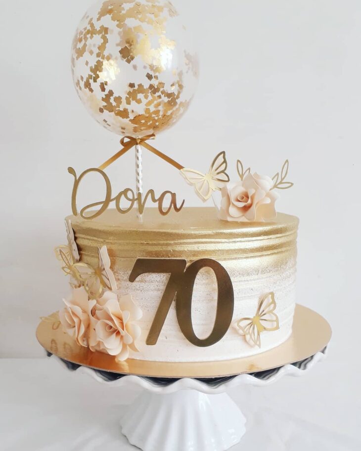 Lindo bolo de aniversário de 70 anos em suporte dourado